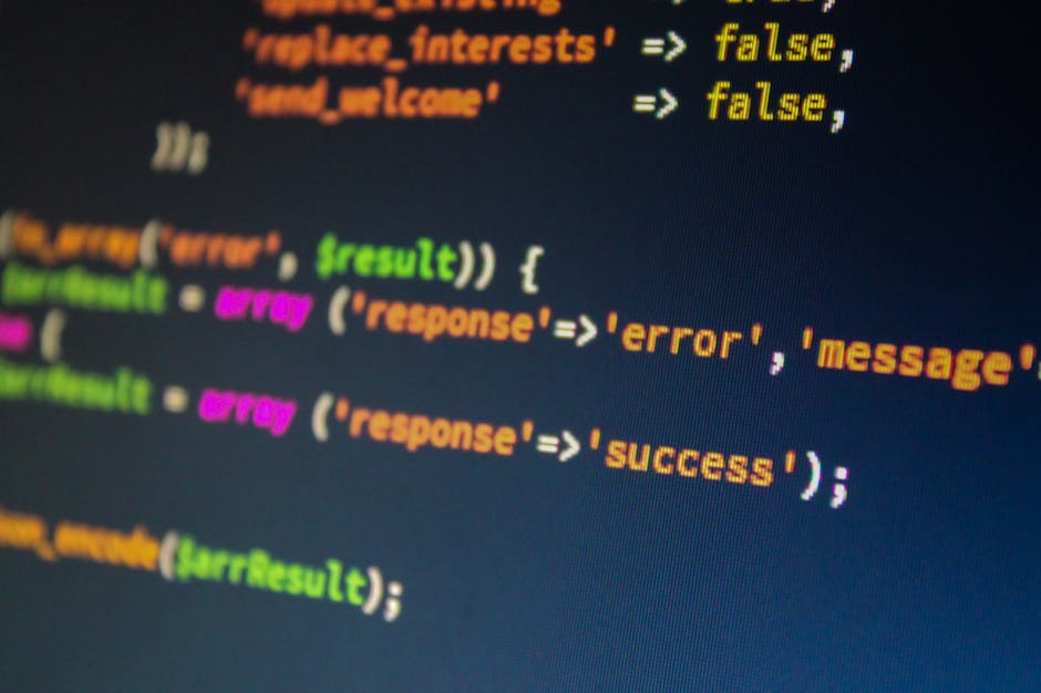 A close-up photograph of a computer screen featuring lines of HTML code in neon green, pink, and white text on a black background. The code includes various tags such as <a>, <li>, and <div> with attr